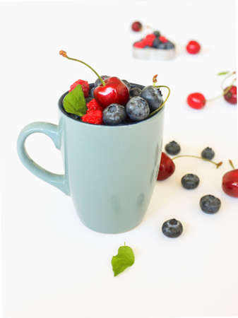 Summer Berries against White Background in the blue cup. Blueberry, raspberry and cherry fresh berries.の写真素材