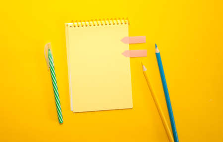 School or office supplies, note pad with blank sheet against yellow background. Flat lay, copy space.の写真素材