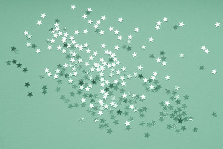 Trendy neo mint background with silver star confetti on green background. Flat lay for holiday, Christmas or party design.の写真素材