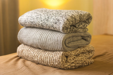 A pile of knitted winter or autumn sweaters on the wood bed. Warm comfortable clothes.