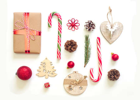 Christmas holiday festive flat lay. Decorations, pine branch and candies against white background. Red and brown colors.の写真素材