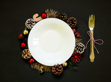 Chirstmas wreath decoration, empty white plate. Flat lay, top view. Black background. Copy space.の写真素材