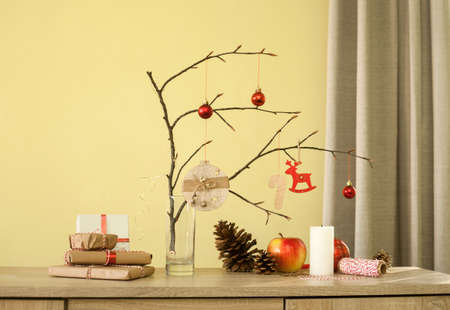 Christmas home decorations. Red balls, branch of tree, gift boxes, candle, pine cones, DIY idea for interior design.の写真素材