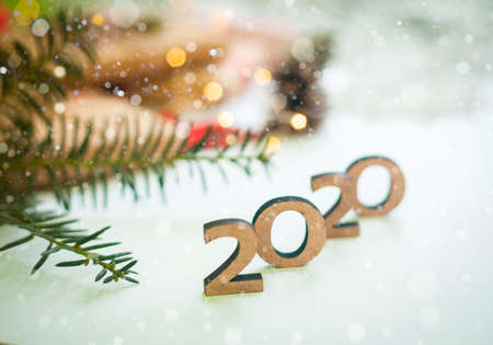 2020 New year wood number with sparkling festive christmas lights bokeh and falling snow. White background and tree.の写真素材