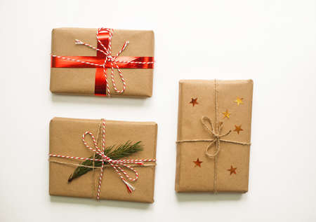 Holiday Christmas gift boxes decorated with red ribbons and pine on white background. Set of three objects for design. Craft paper, DYI.の写真素材