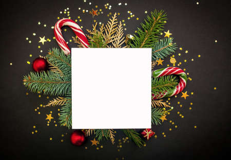 White Christmas mockup for text. Tree branches and candies. Black background with golden confetti. Flat lay, top view. Copy space.の写真素材