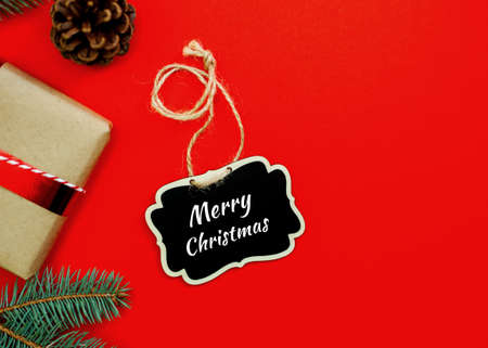 Christmas gifts and tree on red background. Flat lay, top view. Text Merry Christmas on plate. Copy space.の写真素材