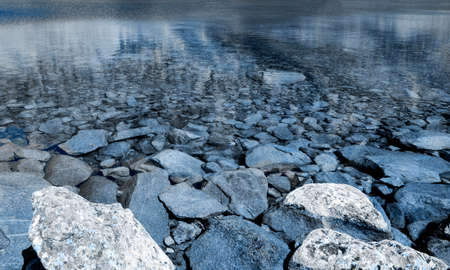 View of beautiful lake with clean water and rocks in the mountains. Trendy 2020 blue toningの写真素材