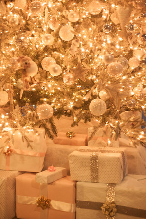 Blurred Christmas tree decoration close up, golden sparkling bokeh background, presents pile, gift...