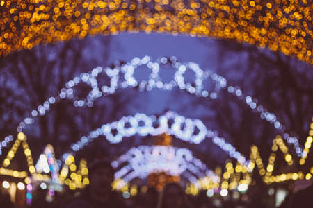 Defocused background of the European Christmas market. Blurred people in the night and bokeh of festive lightsの写真素材