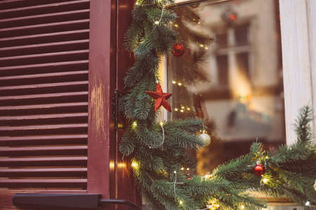 Christmas wreath, decorated window on door in winter made of tree branches, decor, balls and ribbons, holiday design ideaの写真素材