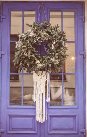 Christmas wreath hanging outside on door in winter made of tree branches, decor, balls and ribbons, holiday design ideaの写真素材