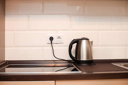 Modern kitchen with metal sink, kettle and white decorative wall, electric cooker, interior design detailsの写真素材