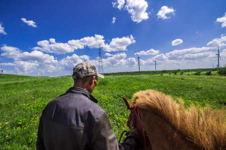 Chinese herdsman and brown horse on grasslandの写真素材