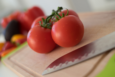 Tomatos and vegetables on wooden cutting boardの写真素材