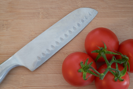 Tomatos and vegetables on wooden cutting boardの写真素材