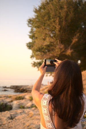woman taking picture of sunset at the beach in Croatiaのeditorial素材