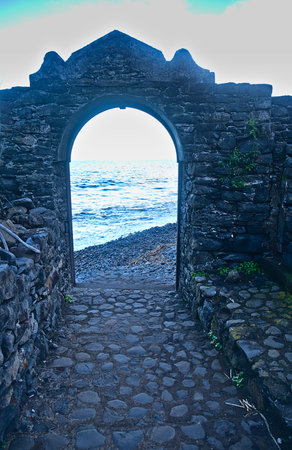Beautiful view of the sea through an old stone arch at sunsetの写真素材