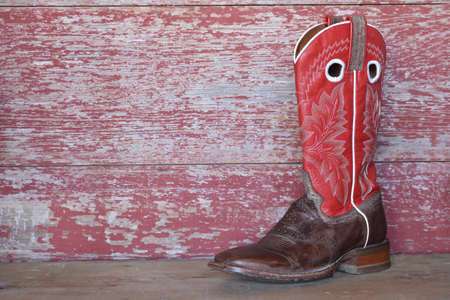 red cowboy boots on red barn boardの写真素材
