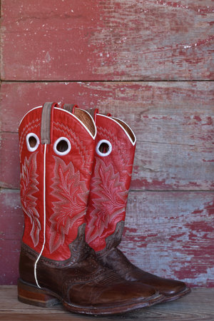 red cowboy boots on red barn boardの写真素材