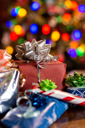 Wrapped Christmas gifts with a Christmas tree in the backgroundの写真素材