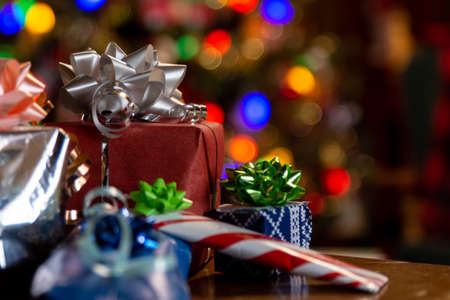 Wrapped Christmas gifts with a Christmas tree in the backgroundの写真素材