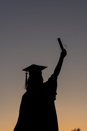 a graduation senior celebrating at sunsetの写真素材