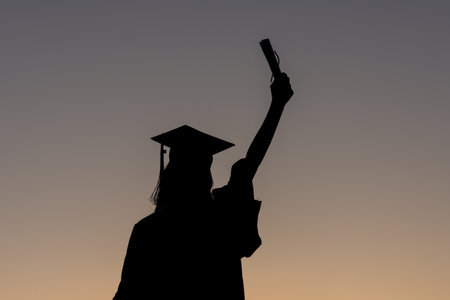 a graduation senior celebrating at sunsetの写真素材