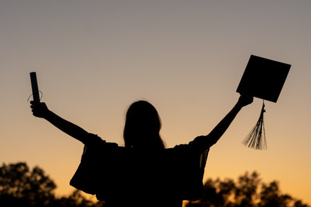 a graduation senior celebrating at sunsetの写真素材