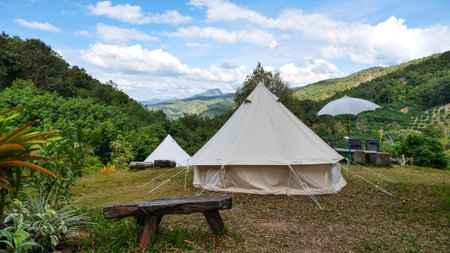 Camping tent front of forest and mountain with blue sky and white clouds / outdoor tourism om...