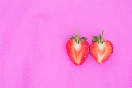 couple red heart the strawberry sweet fruit with seed-studded surface a closeup texture of red berry heart-shaped fruits by half cut on pink fabric background for juice and dessert or valentine themeの写真素材