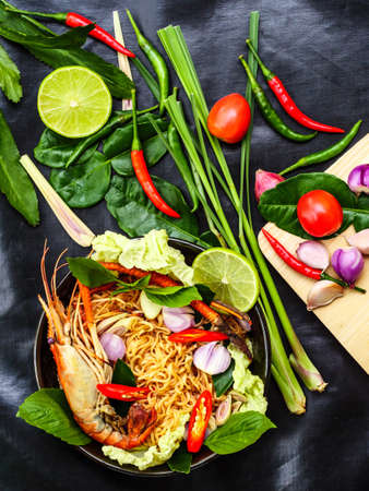dried tom yum kung noodle by top view of spicy and sour fried prawn noodle a healthy thai seafood with herbs ingredient such as chili lemon onion lemon grass and bergamot on black canvas backgroundの写真素材