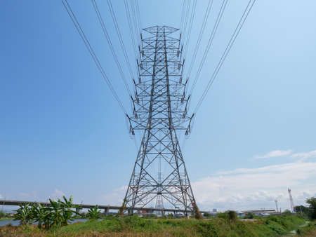 high voltage transmission towers with power line over blue sky background the electricity infrastructure from power plant to industrial and householdの写真素材