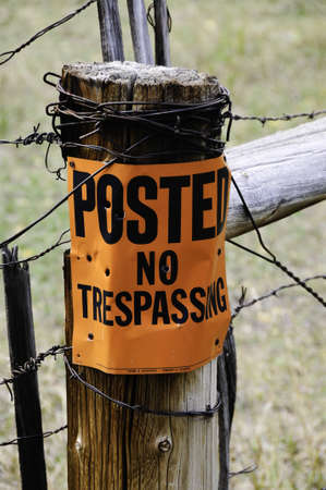 A bright orange no trespassing with bullet holesの写真素材