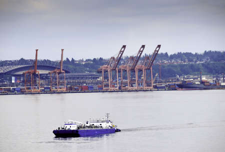 A barge passing in front of shipping containers and cranes at the Port of Seattleの写真素材