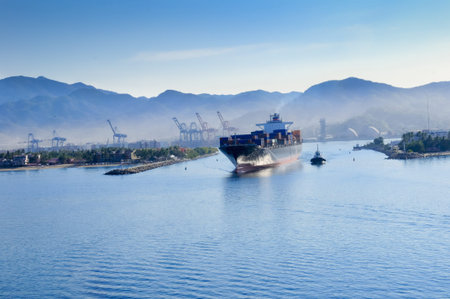 A container ship leaving the harbor at manzanillo, Mexico, with a tug boat