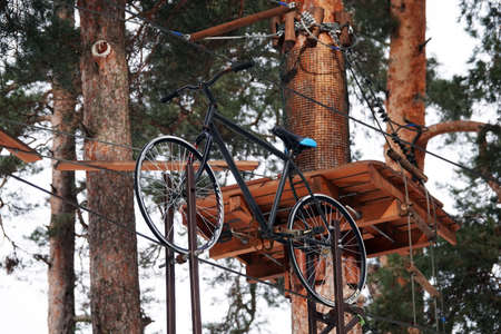 Kiev, Ukraine February 6, 2021: New children's attractions obstacle course need to ride a bike on a tightrope high between the trees in the parkのeditorial素材
