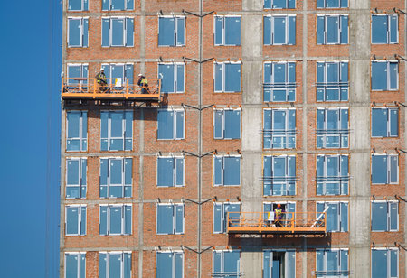 Kiev, Ukraine March 18, 2020: Workers finishing the facade of the building in suspended cradlesのeditorial素材