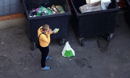 Kiev, Ukraine September 20, 2018: a homeless girl eats directly from the trash can
