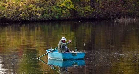 Kiev, Ukraine October 24, 2020: A fisherman catches a fish with a rod from a boat on the riverの写真素材