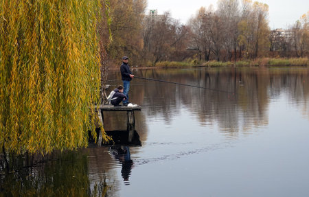 Kiev, Ukraine November 7, 2021: A man and a schoolboy with a backpack on the lake are fishingのeditorial素材