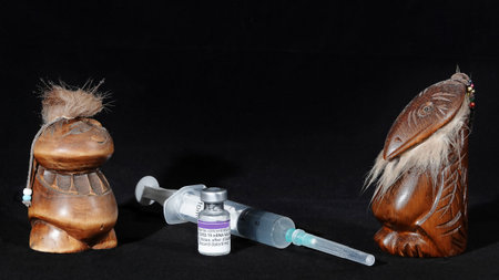 Vaccine against coronavirus COVID-19, syringe filled for vaccination and figurines of Gods in a medical maskのeditorial素材