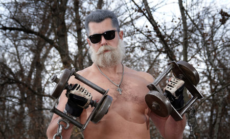 Kyiv, Ukraine November 11, 2021: A young grandfather pumps muscles with a barbell and dumbbells on a...