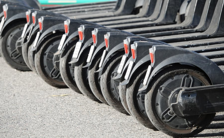 Many electric scooters stand in a row on the city street