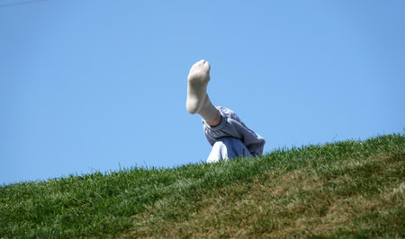 Legs clad in socks, one leg on top of the other, human resting pose on a hillの写真素材