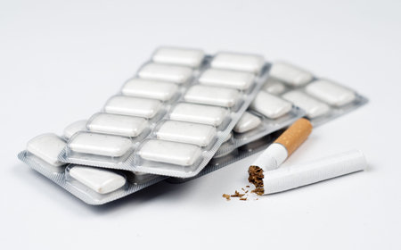 Conceptual photograph for quitting smoking. Broken cigarette in front of nicotine chewing gum disks.