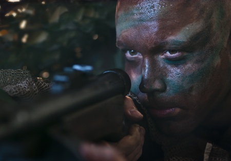 Camouflaged soldier aiming from ambush.の写真素材