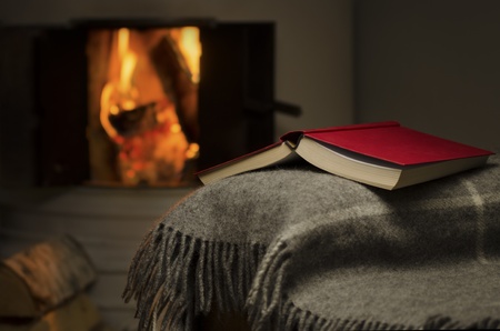Peaceful and warm image of open book resting on a arm rest of a couch  Warm fireplace on background の写真素材