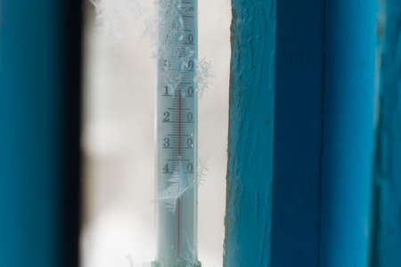thermometer on icy window and frost rime at winterの写真素材