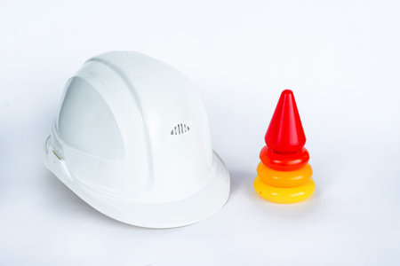 Colored children's pyramid and white helmet of a civil engineer on a white isolated background. The...